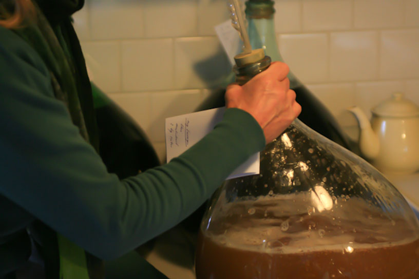 Iemand is wijn aan het maken in een grote glazen vaas